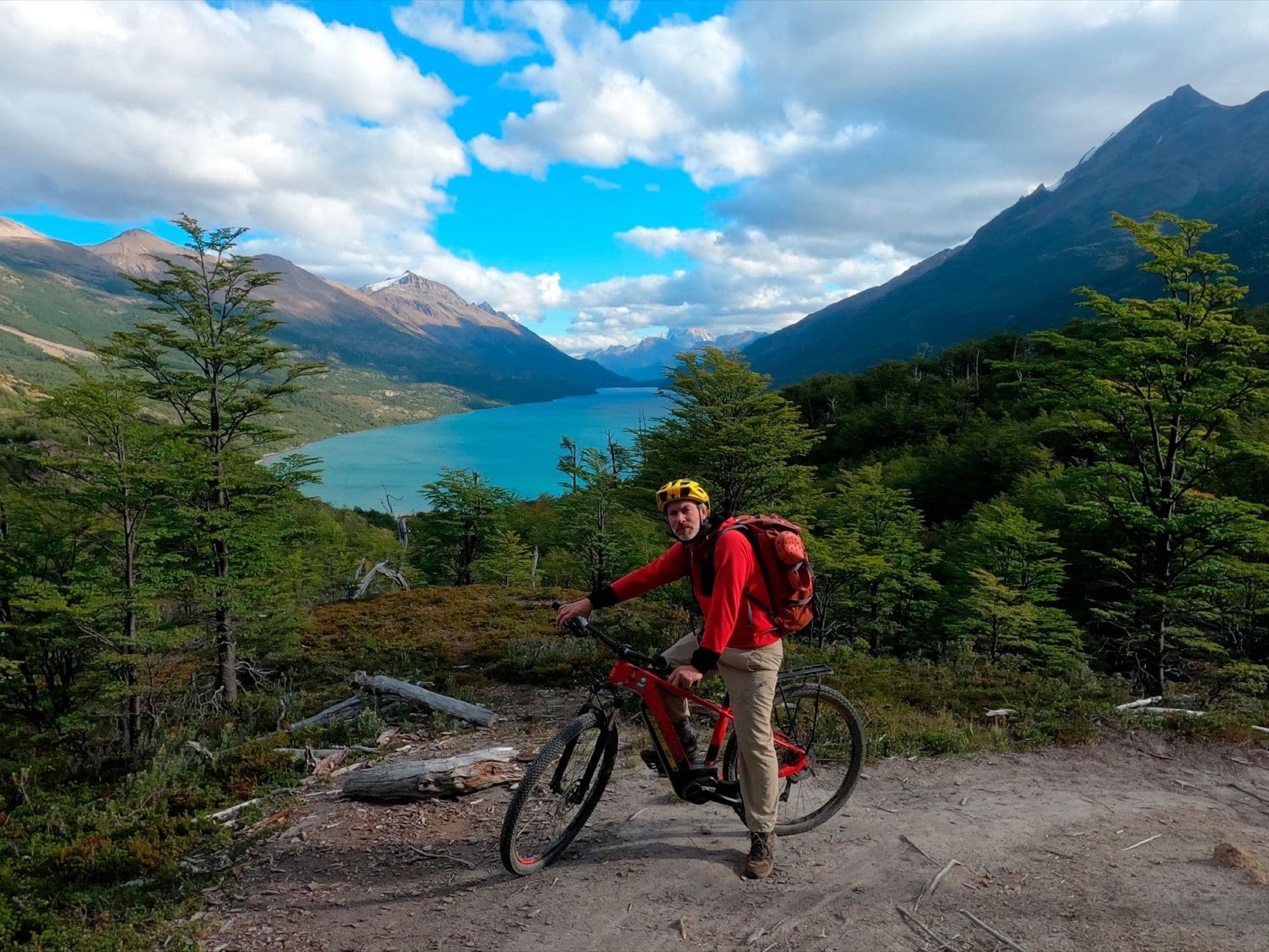 Cyclist with a loaded bicycle at a lookout with a view of Lago del Desierto and Cerro Fitz Roy