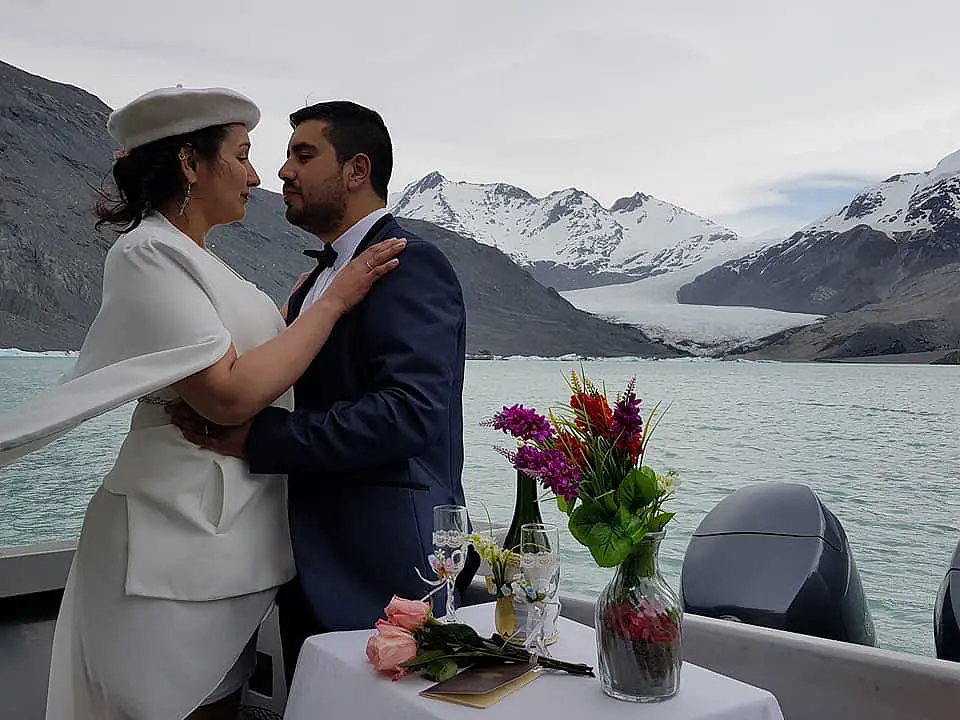 Mariana and Jonathan embracing on board, with the O'Higgins Glacier in the background